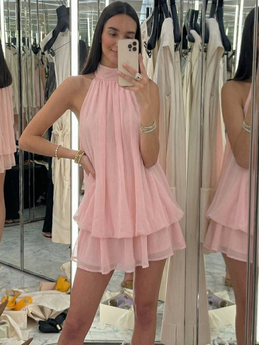 Woman taking a mirror selfie wearing a pink dress in a fitting room.